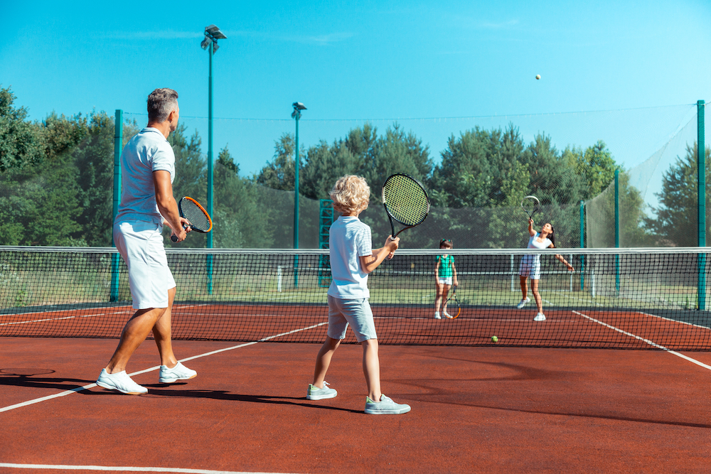 A family of four play tennis
